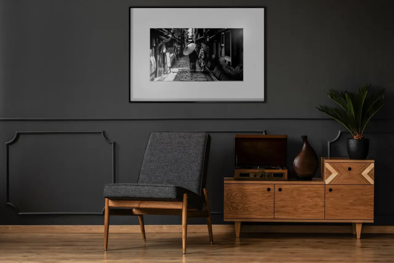 Dans un salon aux murs sombres, un cadre encadre une photographie en noir et blanc d'une ruelle ; rien ne distingue l'&eacute;cran &agrave; encre &eacute;lectronique d'un tirage sous verre