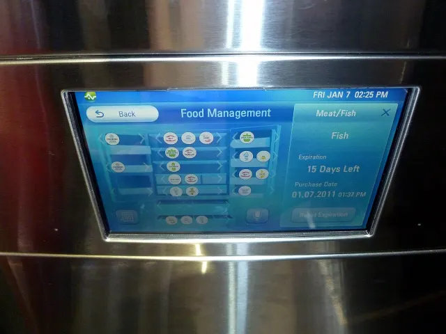 Gros plan sur un &eacute;cran tactile encastr&eacute; dans la porte inox d'un r&eacute;frig&eacute;rateur. L'interface, bleue, s'intitule &laquo; Food Management &raquo; ; &agrave; droite, un panneau indique &laquo; Fish &raquo;, &laquo; Expiration : 15 Days Left &raquo;, &laquo; Purchase Date 01.07.2011 &raquo;. En haut &agrave; droite de l'&eacute;cran, &laquo; FRI JAN 7 02:25 PM &raquo;.